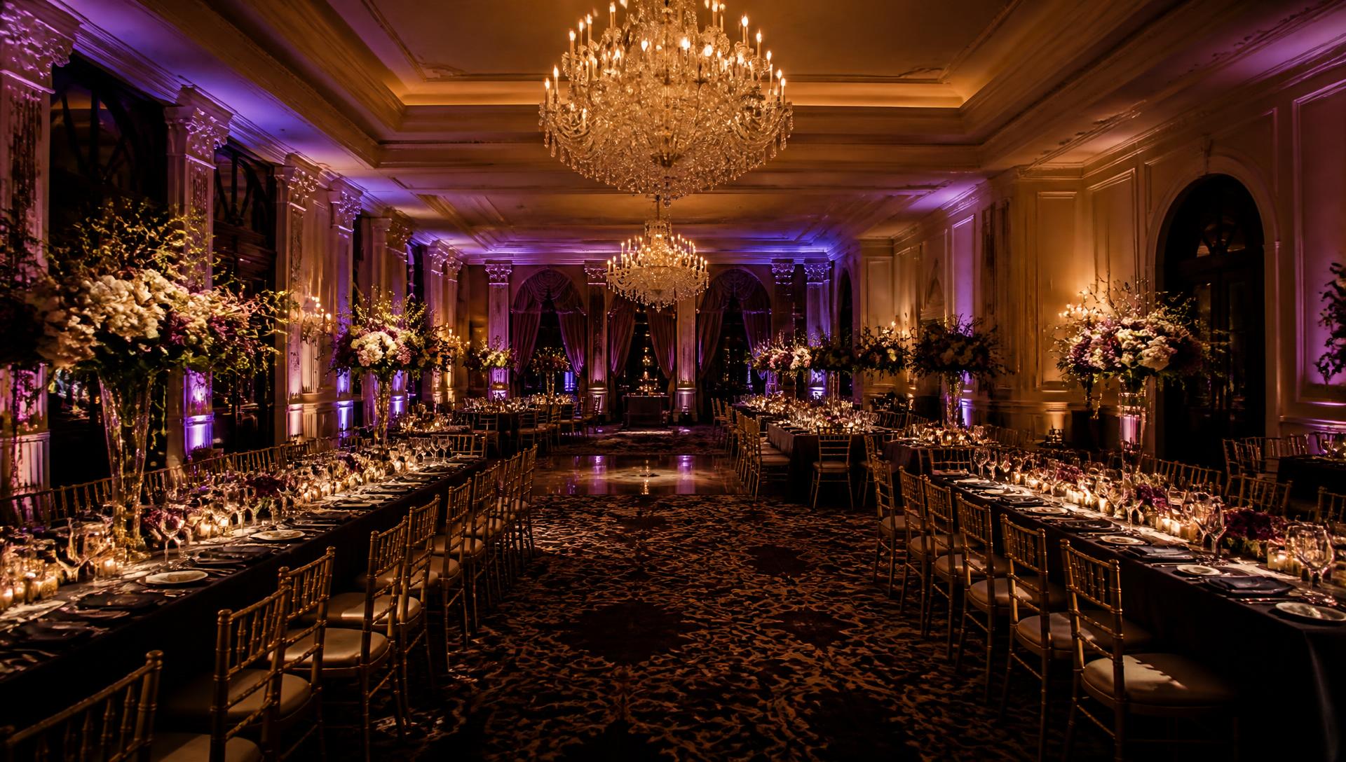 Ballroom set for a formal evening event with chandeliers and candlelit tables